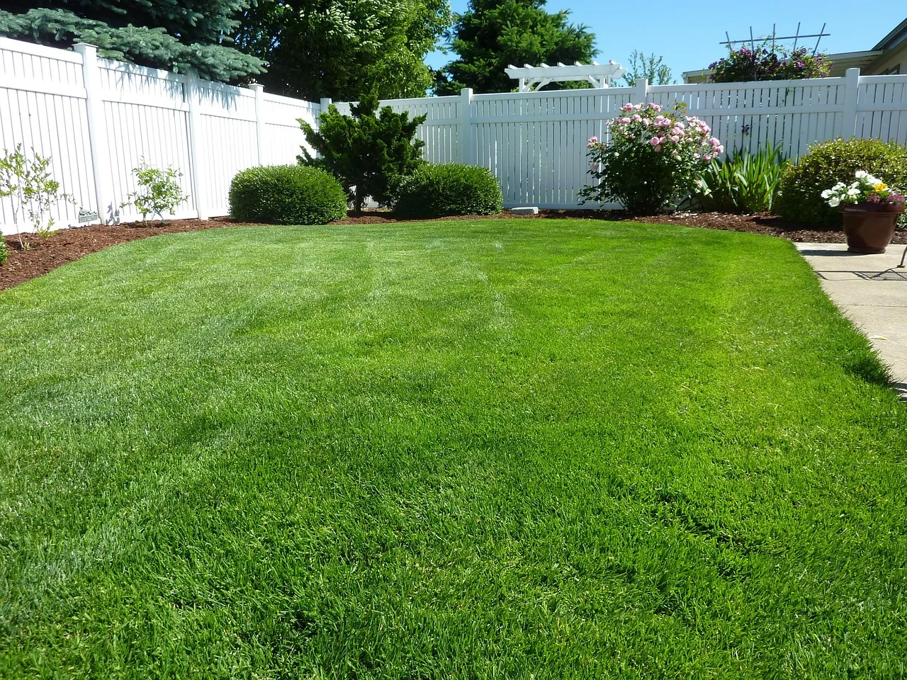 White vinyl privacy fence surrounding a landscaped backyard