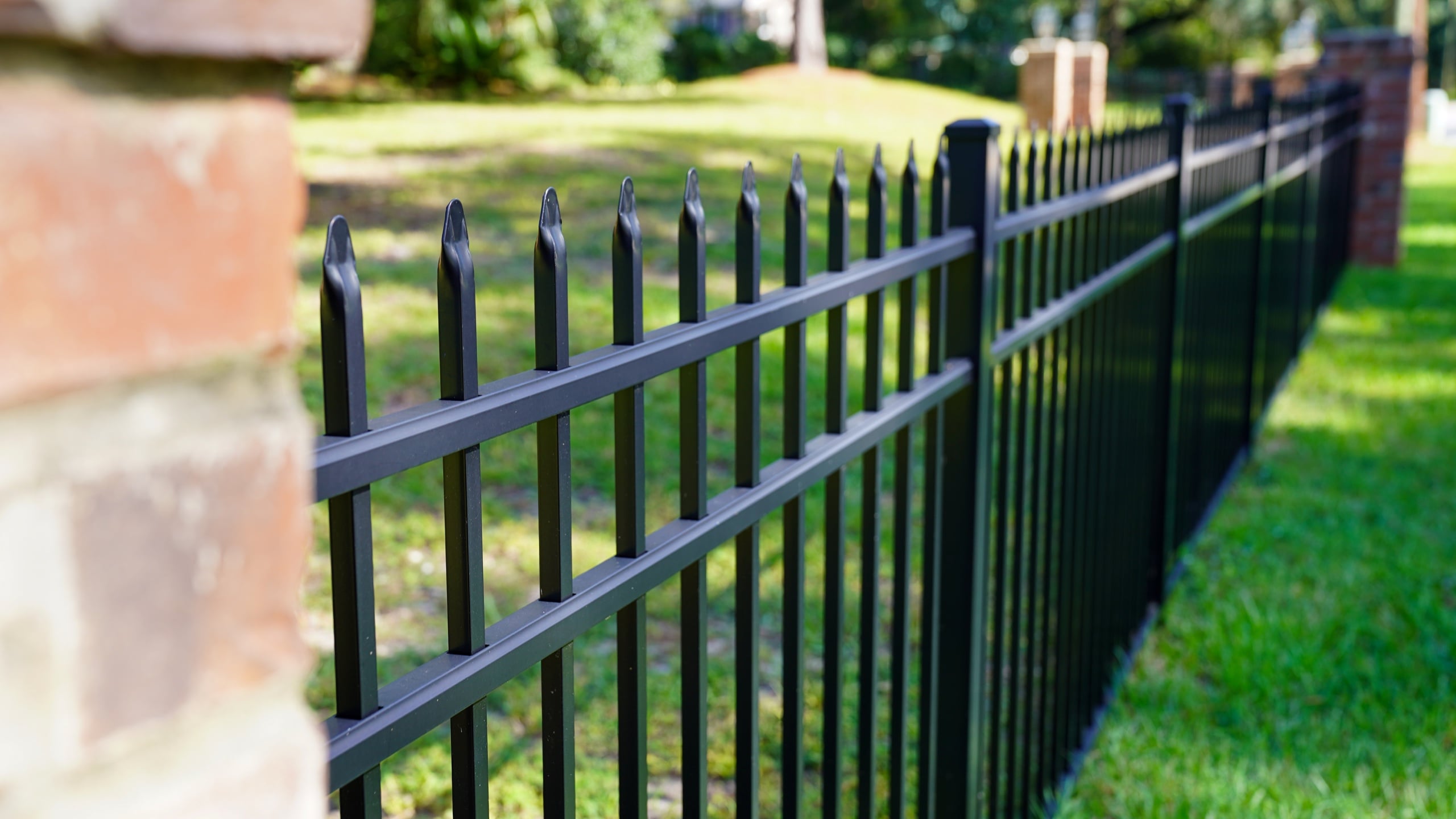 Black ornamental fence with brick columns installed by Floyd Fence